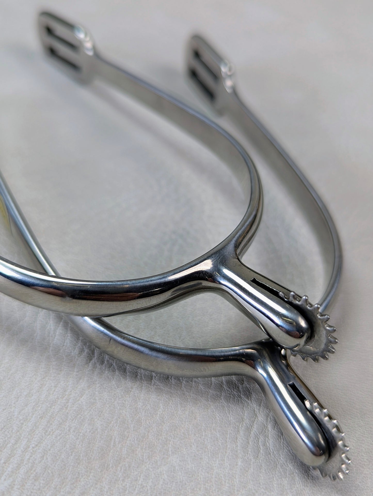 closeup of silver english riding spurs with small rowels on a textured background