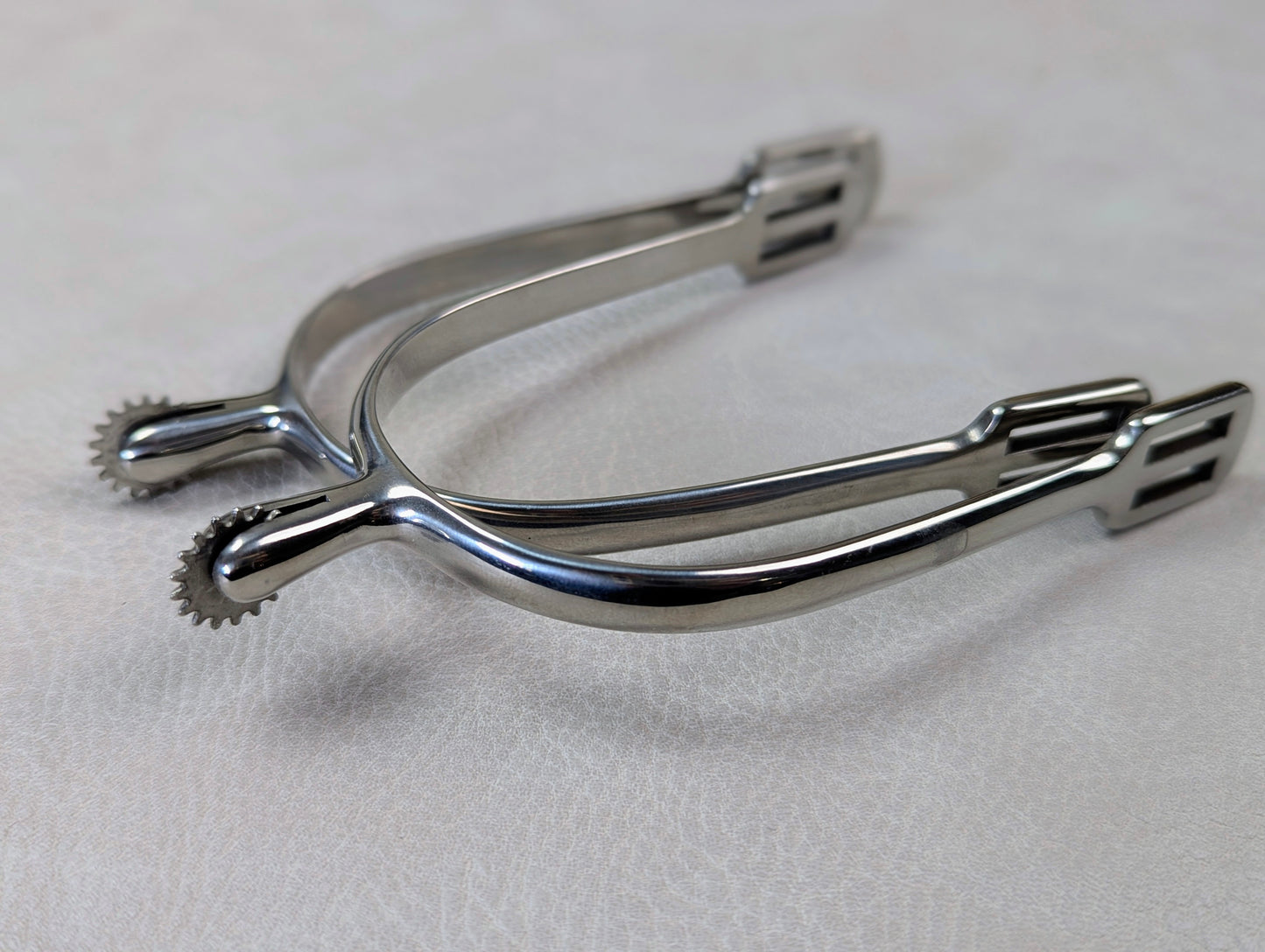 silver english spurs with small rowel on a textured grey table
