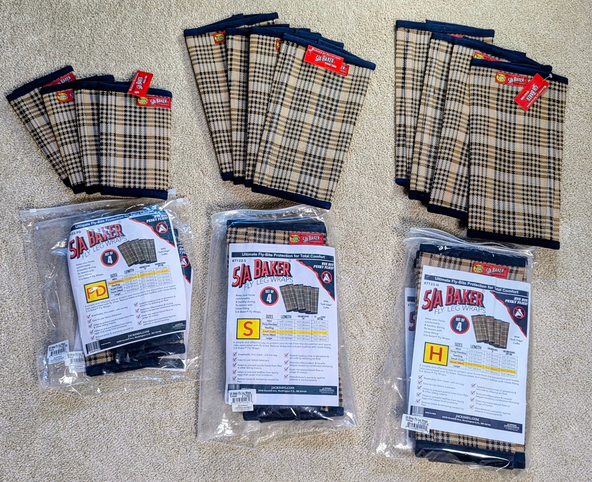Three packages of BAKER fly boots in sizes S, M, and L, arranged alongside loose stacks of the same product on a beige carpet background.