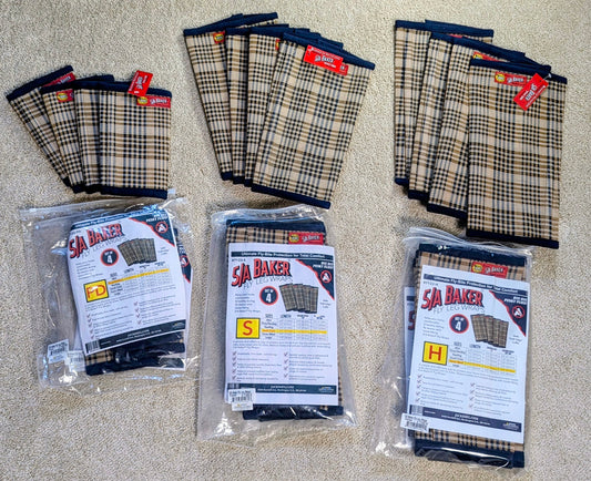 Three packages of BAKER fly boots in sizes S, M, and L, arranged alongside loose stacks of the same product on a beige carpet background.