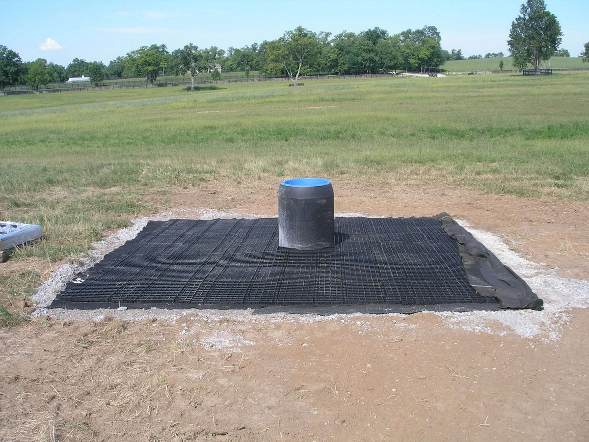 Pasture waterer surrounded by Stall Grid panels, creating a stable, well‑drained surface that reduces mud and erosion.