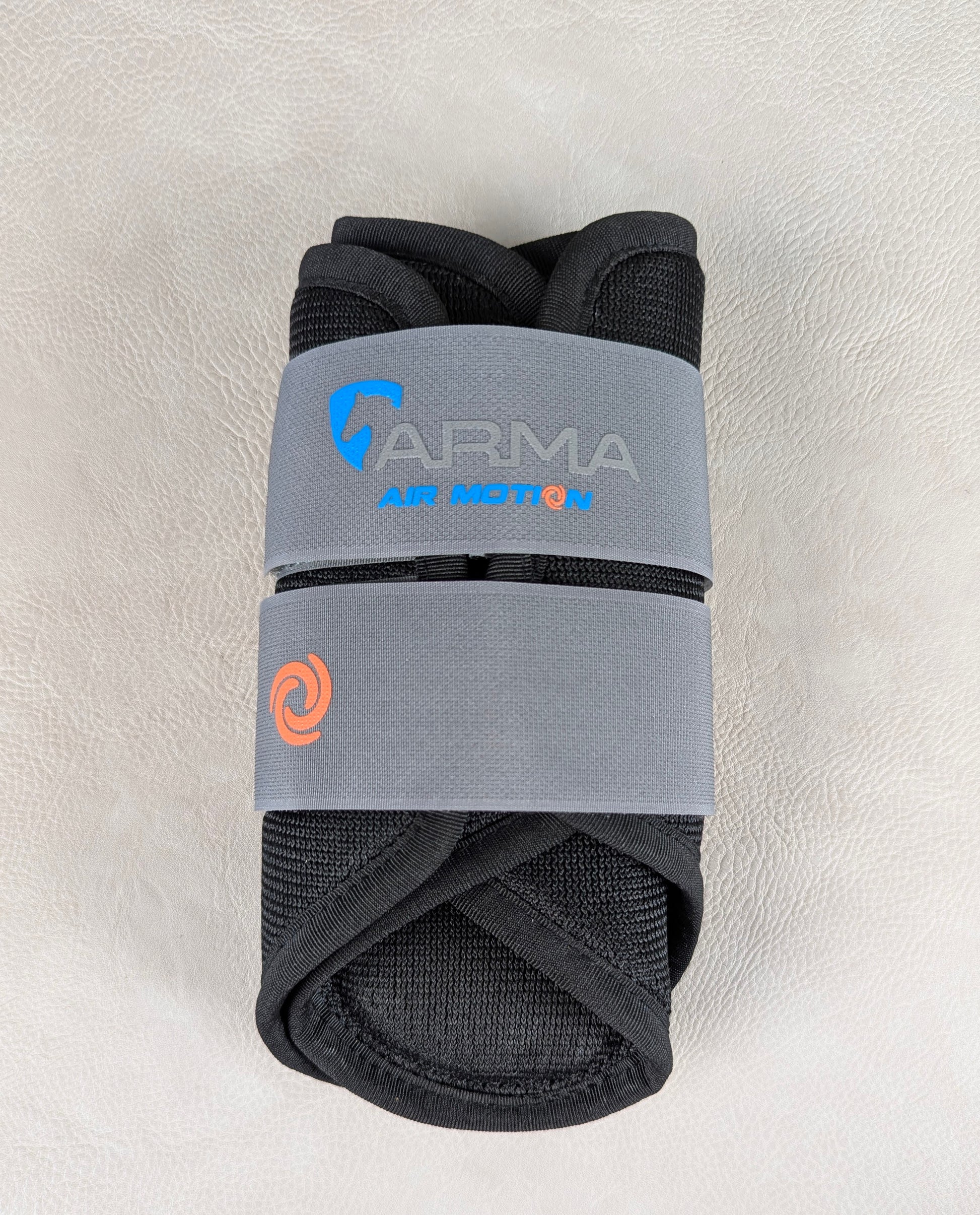 A rolled black ARMA Air Motion brushing boot wrapped in a gray elastic band, showing the breathable mesh material and Air Motion branding.