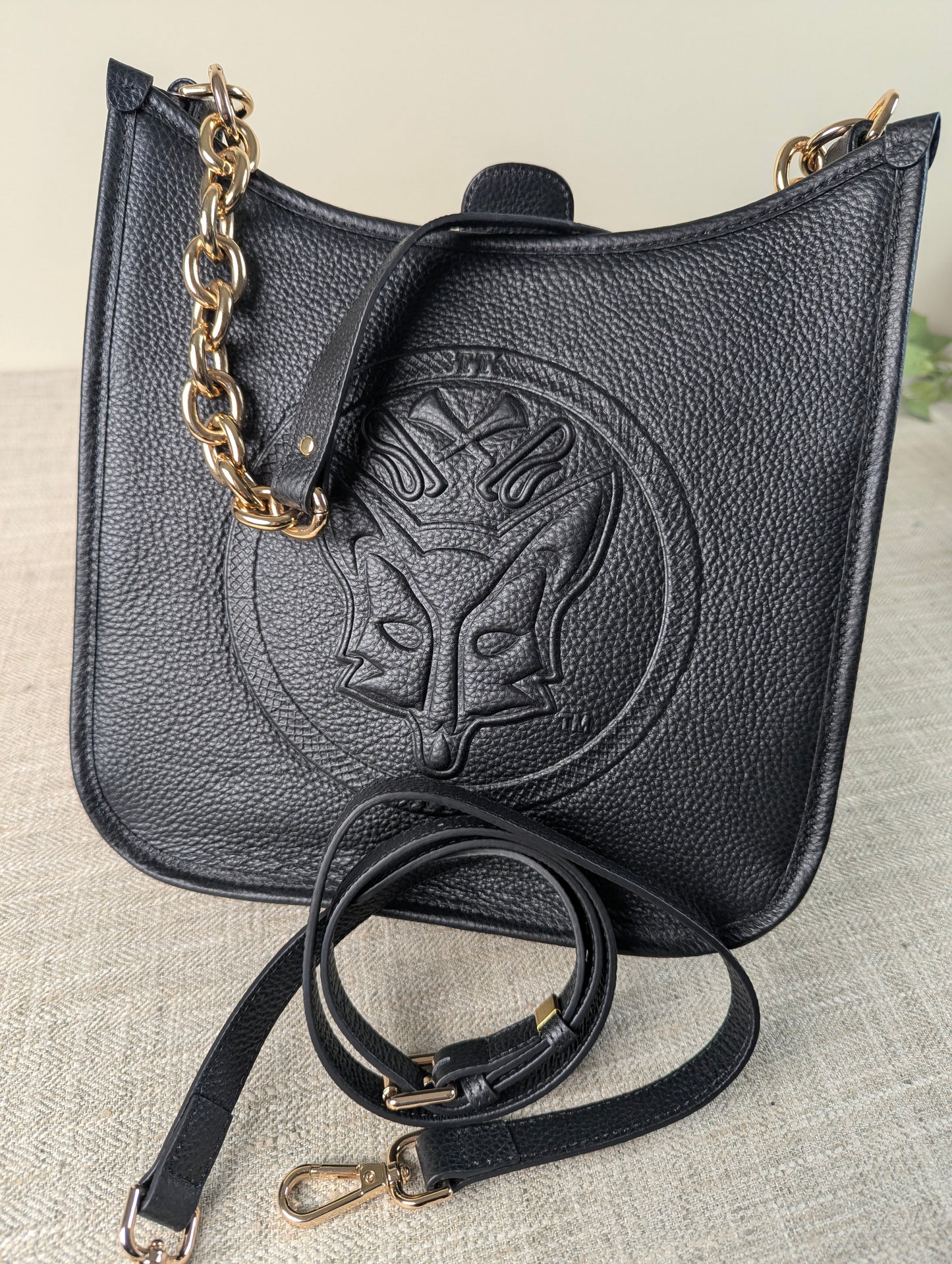 Black Tucker Tweed Middleburg Messenger purse displayed on a neutral background, featuring embossed equestrian artwork, gold hardware, a chunky gold chain, and a detachable leather crossbody strap.