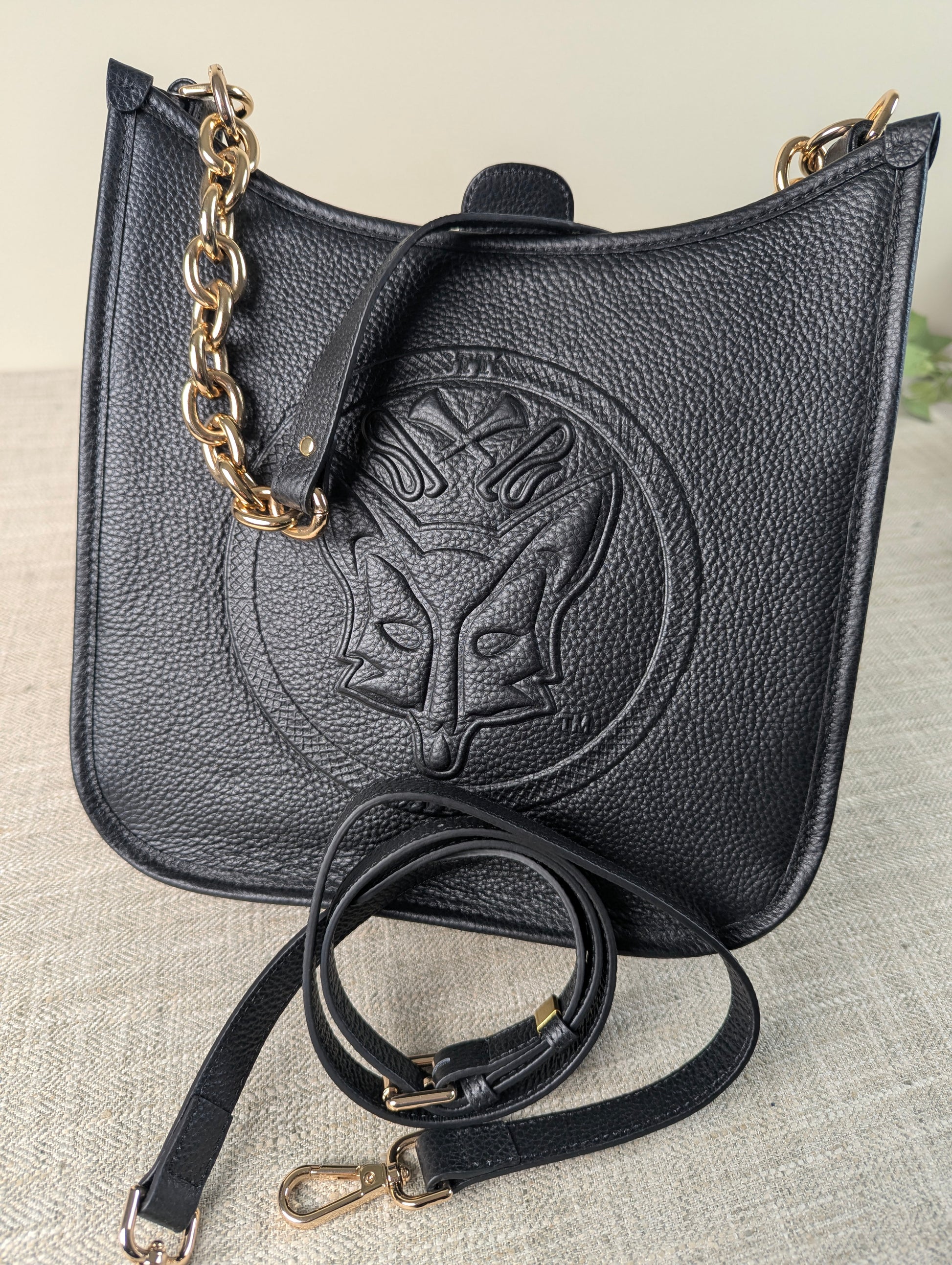 Black Tucker Tweed Middleburg Messenger purse displayed on a neutral background, featuring embossed equestrian artwork, gold hardware, a chunky gold chain, and a detachable leather crossbody strap.