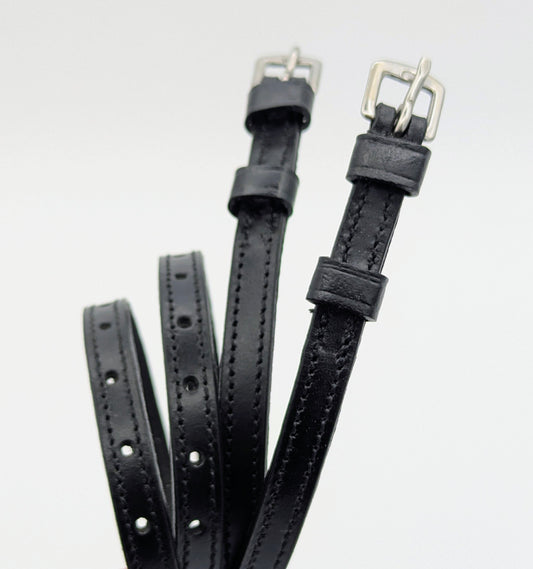 Black ladies’ leather spur straps with square stainless steel buckles and double keepers, shown laid out to display stitching and adjustment holes.