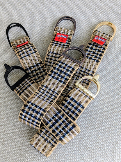 Three Limited Edition 5/A Baker × Ellany elastic belts arranged on a textured surface, each featuring signature Baker plaid and a different metal buckle finish—black, copper, and yellow‑gold—with red Baker labels visible.