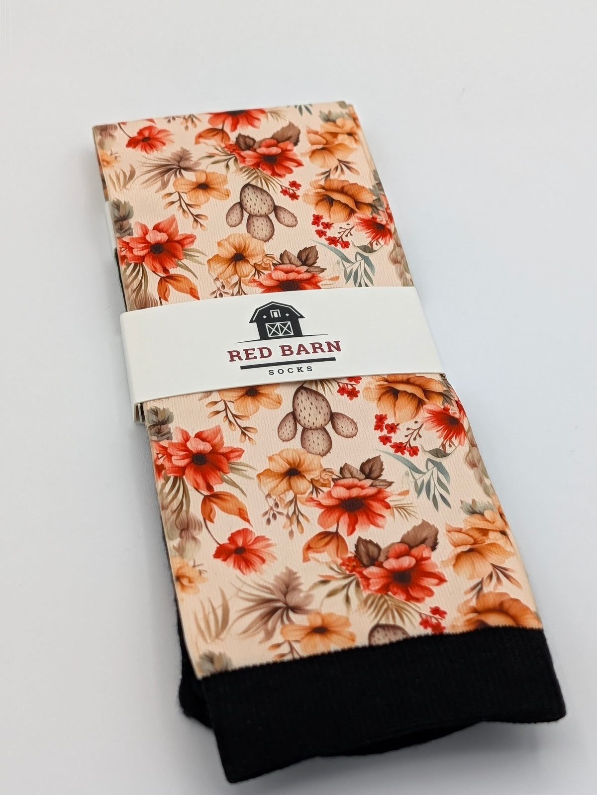 Close‑up of Harvest Blooms tall socks with cushioned black footbed and multicolor fall floral pattern on a grey surface