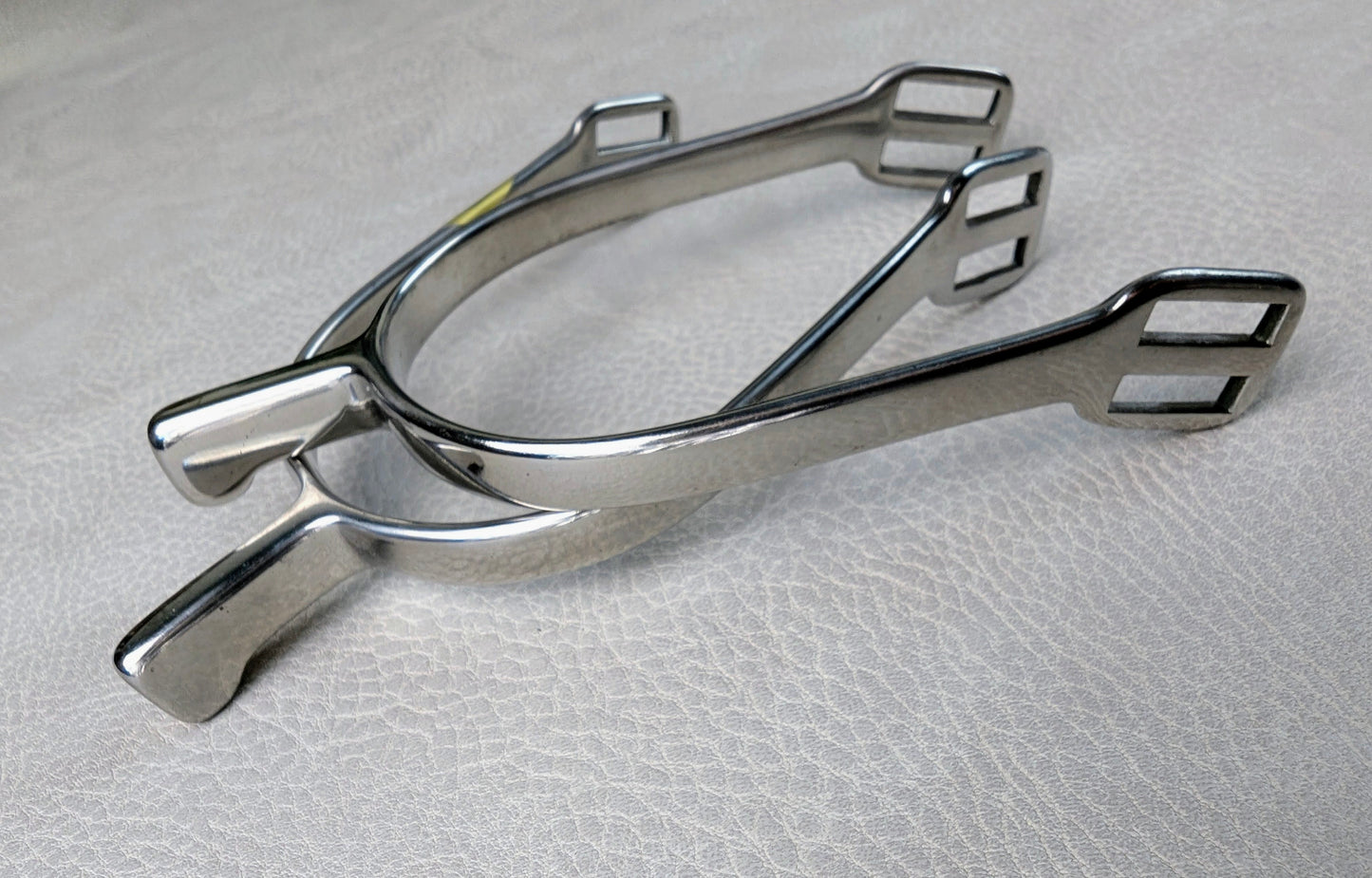 Stainless steel ladies hammerhead spurs with 25mm neck and rounded ends, shown on a light textured surface.