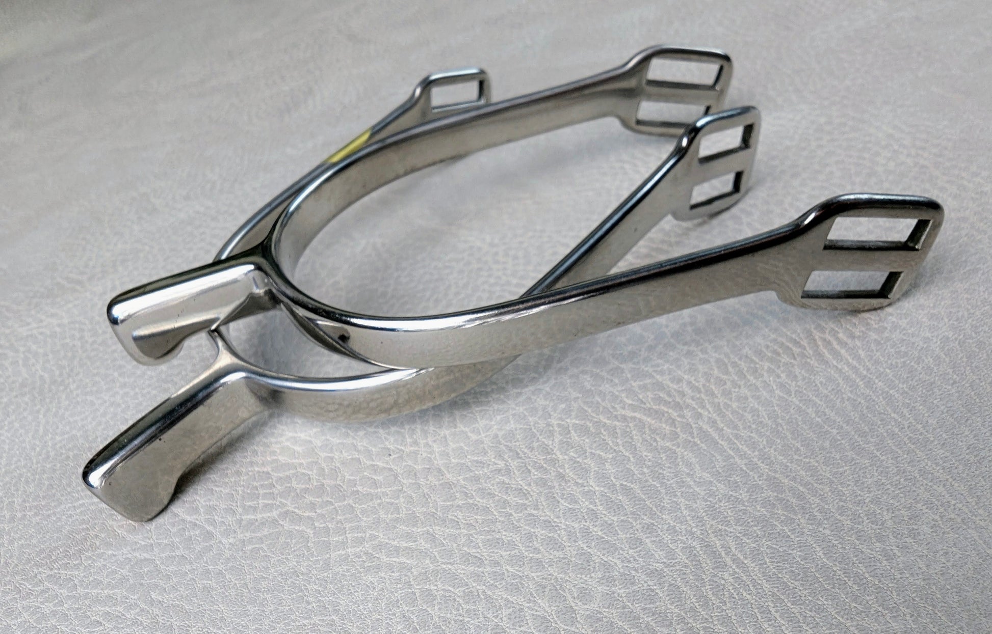 Stainless steel ladies hammerhead spurs with 25mm neck and rounded ends, shown on a light textured surface.