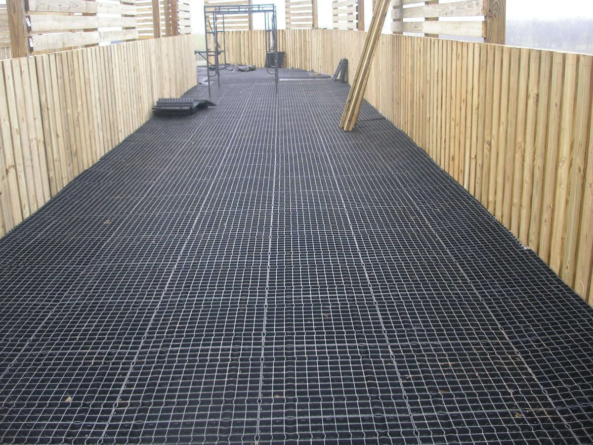Stall Grid equine flooring used as the foundation layer in a horse walker lane, providing drainage and structural support.