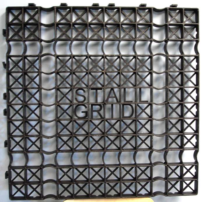Interlocking Stall Grid flooring panel showing structural cross‑supports and raised “STALL GRID” logo.