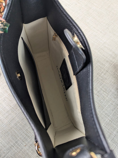 Interior of the Tucker Tweed Middleburg Messenger purse showing the light beige lining, gold hardware, interior zip pocket, and branded leather patch.