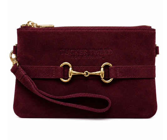 Merlot suede Wellington wristlet with gold hardware and snaffle‑bit detail, shown from the front with embossed Tucker Tweed branding and attached wrist strap.