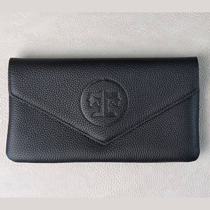 A black pebbled leather envelope-style wallet with a circular embossed monogram logo on the front, displayed on a light textured surface.